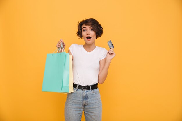 Retrato de una mujer feliz sorprendida sosteniendo bolsas de compras