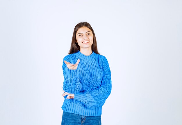 Retrato de mujer feliz en suéter azul posando en blanco.