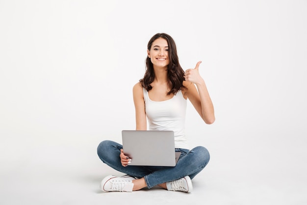 Retrato de una mujer feliz vestida con una camiseta sin mangas con laptop