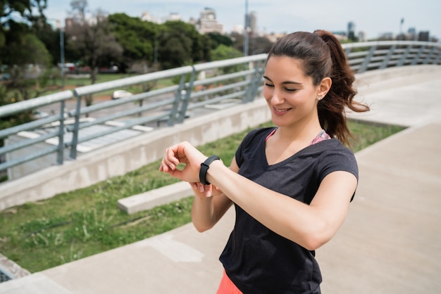 Retrato de una mujer fitness comprobar el tiempo en su reloj inteligente. Concepto de deporte y estilo de vida saludable.