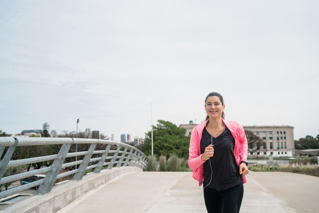 Retrato de una mujer fitness corriendo al aire libre en la calle. Concepto de deporte y estilo de vida saludable.