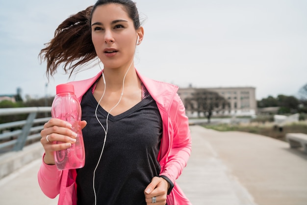 Retrato de una mujer fitness corriendo al aire libre en la calle. Concepto de deporte y estilo de vida saludable.