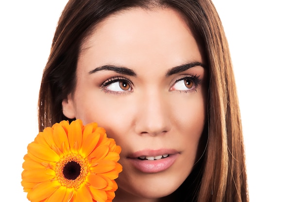 Retrato de mujer con flor de naranja sobre fondo blanco.