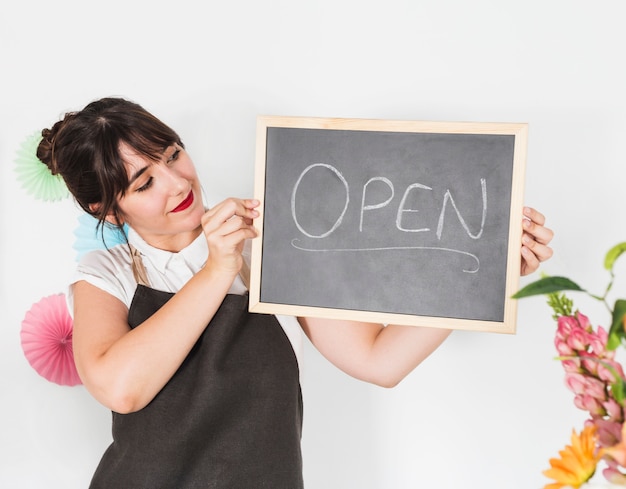 Retrato de una mujer florista con pizarra mostrando palabra abierta