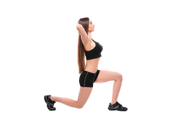 Retrato de mujer en forma deportiva en ropa deportiva trabajando, haciendo ejercicios aislado sobre fondo blanco.