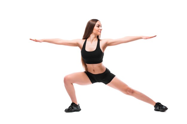 Retrato de mujer en forma deportiva en ropa deportiva trabajando, haciendo ejercicios aislado sobre fondo blanco.