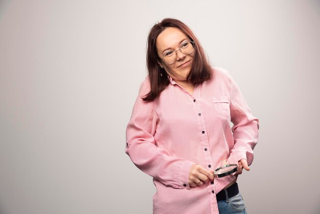 Retrato de mujer frotando una lupa sobre un fondo blanco. Foto de alta calidad