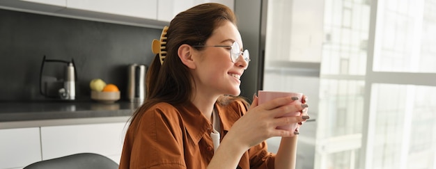 Foto gratuita retrato de mujer con gafas sonriendo y riendo sosteniendo una taza de té bebiendo café en