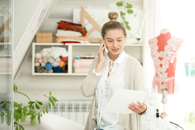 Retrato de mujer hablando por teléfono, vestido de maniquí detrás