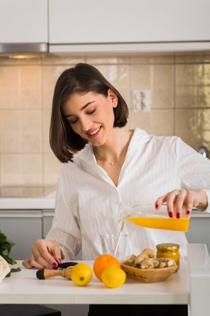 Retrato de mujer haciendo jugo de naranja fresco