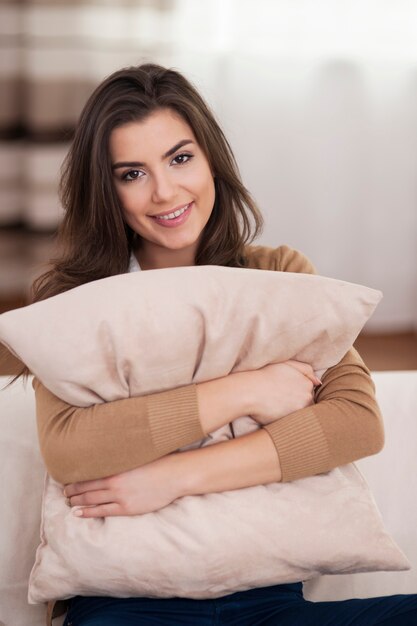Retrato de mujer hermosa abrazando la almohada en el sofá