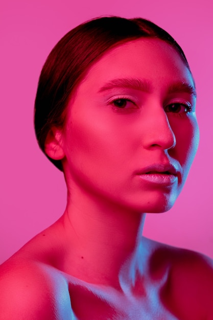 Retrato de mujer hermosa aislado sobre fondo de estudio rosa en luz de neón, monocromo. Modelo de mujer hermosa. Concepto de emociones humanas, expresión facial, ventas, publicidad, moda y belleza.