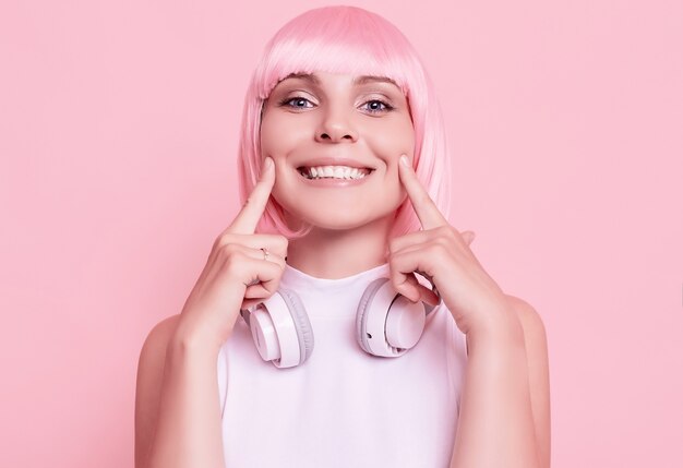 Retrato de mujer hermosa con cabello rosado disfruta de la música en auriculares