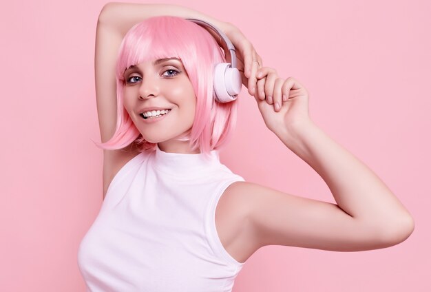 Retrato de mujer hermosa con cabello rosado disfruta de la música en auriculares