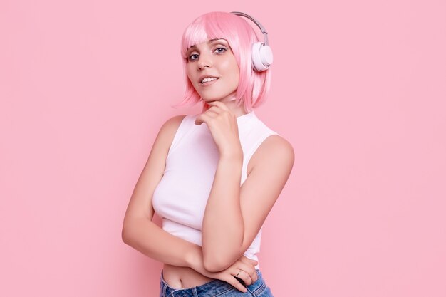 Retrato de mujer hermosa con cabello rosado disfruta de la música en auriculares