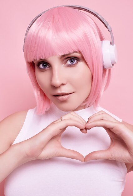 Retrato de mujer hermosa con cabello rosado disfruta de la música en auriculares