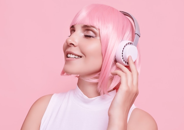 Retrato de mujer hermosa con cabello rosado disfruta de la música en auriculares