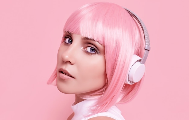 Retrato de mujer hermosa con cabello rosado disfruta de la música en auriculares