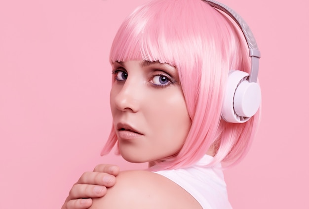 Retrato de mujer hermosa con cabello rosado disfruta de la música en auriculares