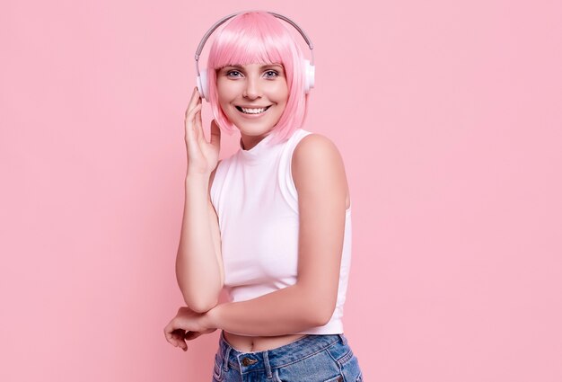 Retrato de mujer hermosa con cabello rosado disfruta de la música en auriculares