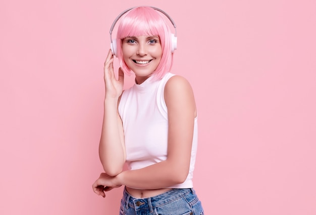 Retrato de mujer hermosa con cabello rosado disfruta de la música en auriculares