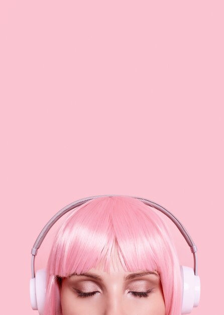 Retrato de mujer hermosa con cabello rosado disfruta de la música en auriculares