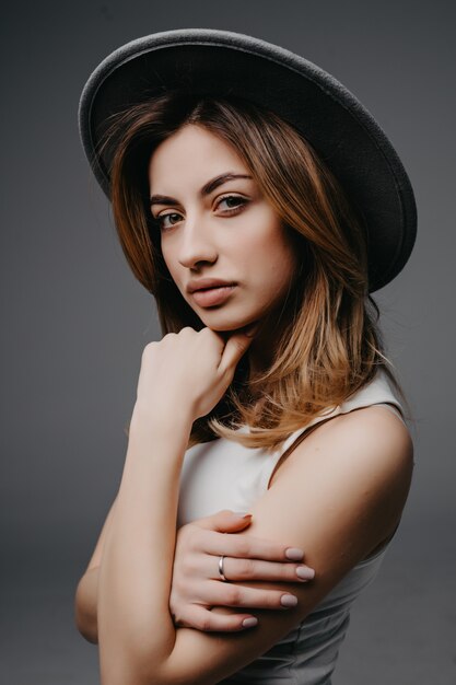 Retrato de mujer hermosa elegante con sombrero aislado en gris