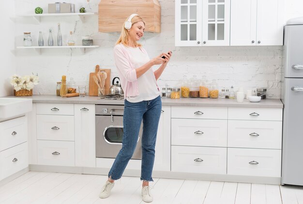 Retrato de mujer hermosa escuchando música en la cocina