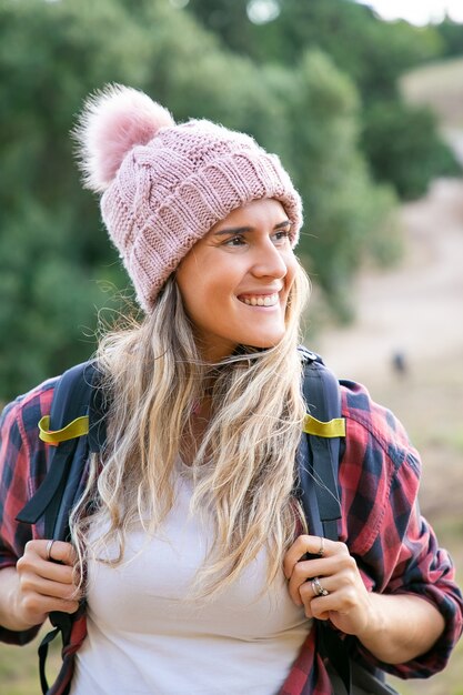 Retrato de mujer hermosa feliz con sombrero y mochila de transporte. Caucásico, sonriente, mujer viajera, posición, en, nature., Viaje, turismo, aventura, y, verano, vacaciones, concepto