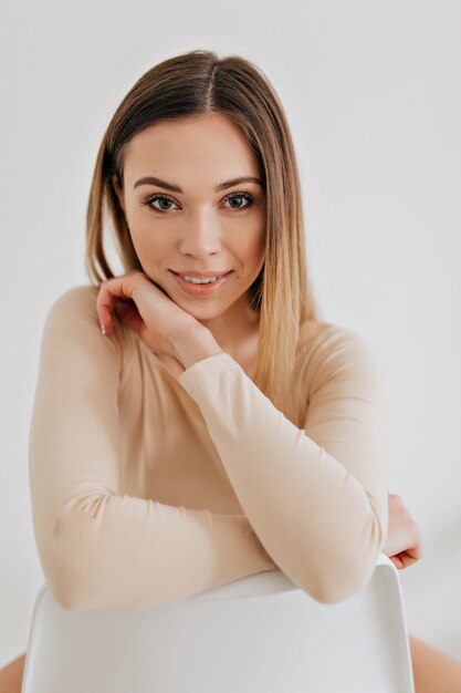 Retrato de mujer hermosa joven adorable, aislada sobre fondo blanco, mirando a cámara, mirada concentrada. Foto de estudio hermosa cara chica caucásica con maquillaje natural