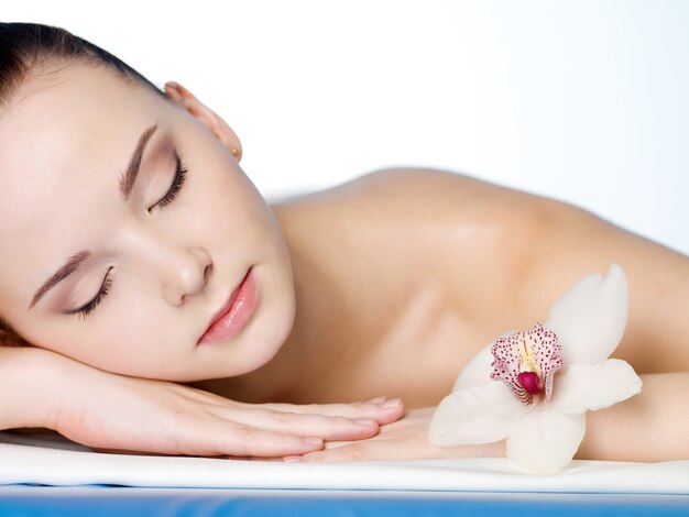 Retrato de mujer hermosa joven descansando en el salón de belleza spa con flor