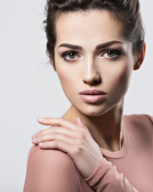 Retrato de una mujer hermosa joven con maquillaje de ojos ahumados. Chica adulta bastante joven posando en el estudio. Primer rostro femenino atractivo.