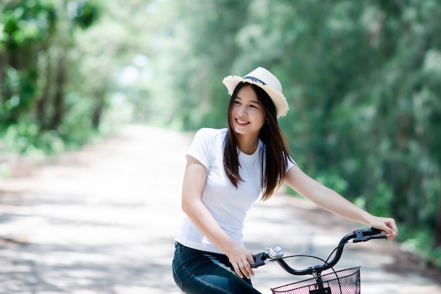Retrato de la mujer hermosa joven que monta una bicicleta en un parque.