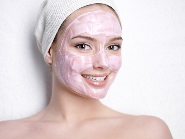 Retrato de mujer hermosa joven sonriente con máscara de belleza facial rosa