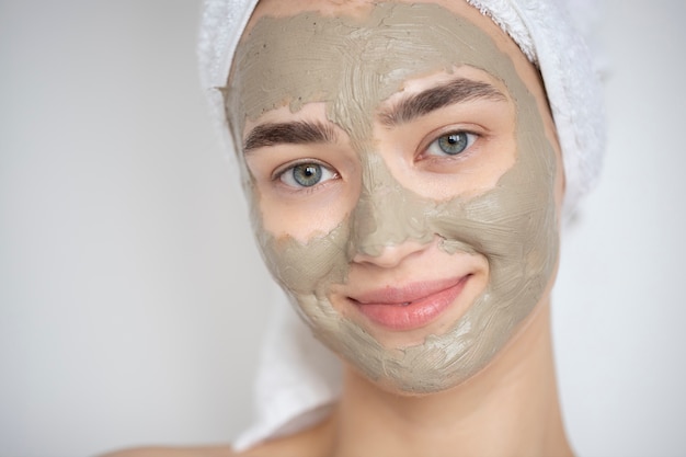 Retrato de mujer hermosa con máscara de arcilla de belleza en su rostro