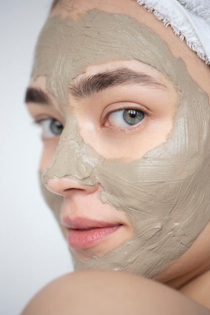 Retrato de mujer hermosa con máscara de arcilla de belleza en su rostro