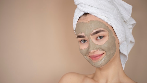 Retrato de mujer hermosa con máscara de arcilla de belleza en su rostro