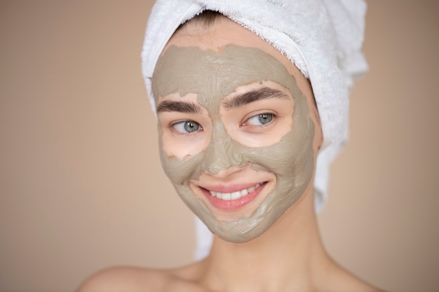 Retrato de mujer hermosa con máscara de arcilla de belleza en su rostro