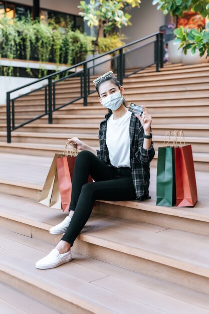 Retrato de mujer hermosa en máscara coloque anteojos en la cabeza sosteniendo la bolsa de compras