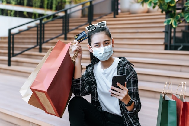 Retrato de mujer hermosa en máscara coloque anteojos en la cabeza sosteniendo la bolsa de compras