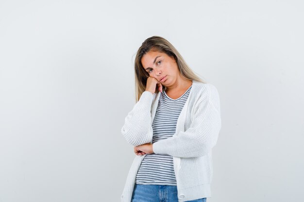 Foto gratuita retrato de mujer hermosa con la mejilla inclinada en la mano en la chaqueta y mirando pensativo vista frontal