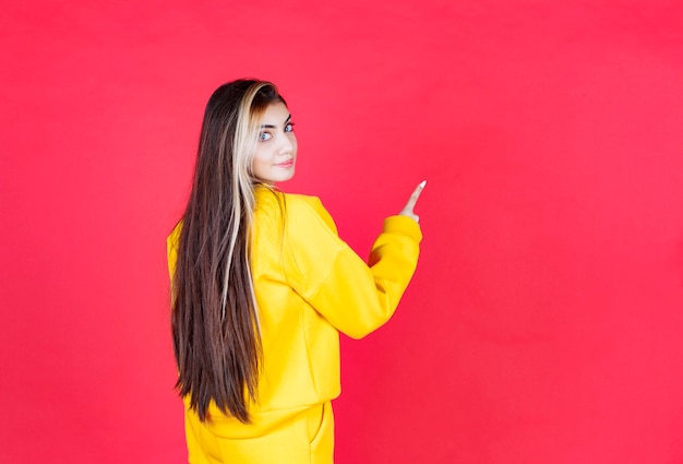 Retrato de mujer hermosa modelo de pie y apuntando hacia arriba con el dedo