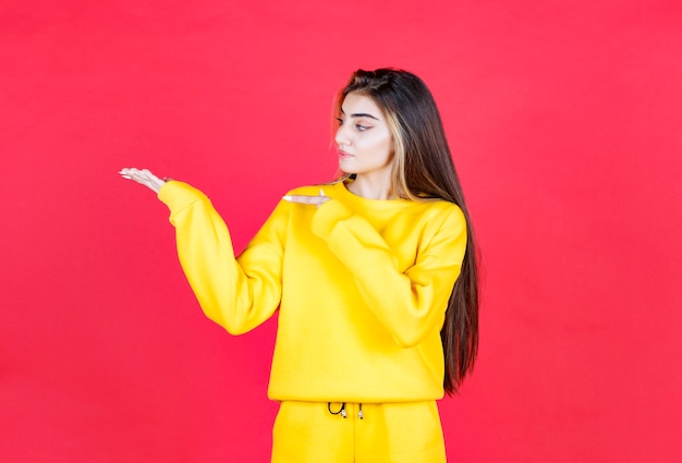 Retrato de mujer hermosa modelo de pie y apuntando a la palma abierta