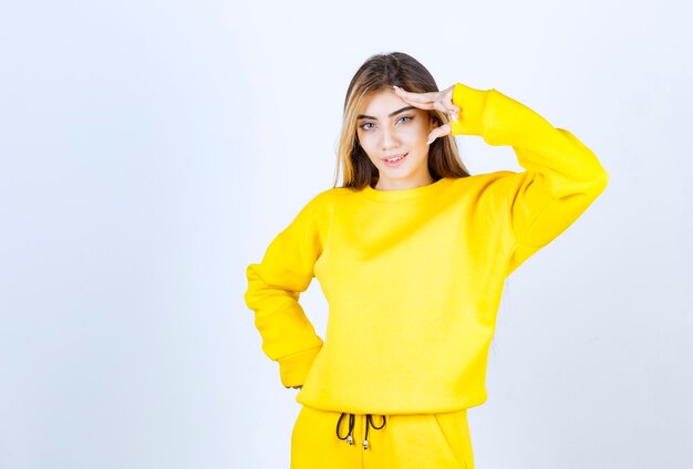 Retrato de mujer hermosa modelo de pie y posando en camiseta amarilla