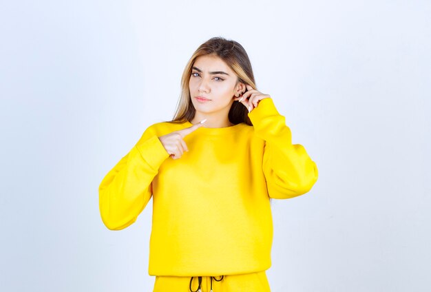 Retrato de mujer hermosa modelo de pie y posando en camiseta amarilla