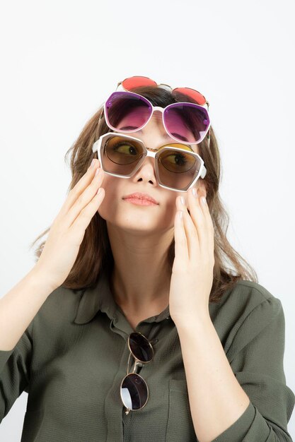 Retrato de mujer hermosa con muchas gafas de sol sobre blanco. foto de alta calidad