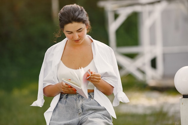 Retrato de mujer hermosa. La mujer lee un libro. Dama con camisa blanca.