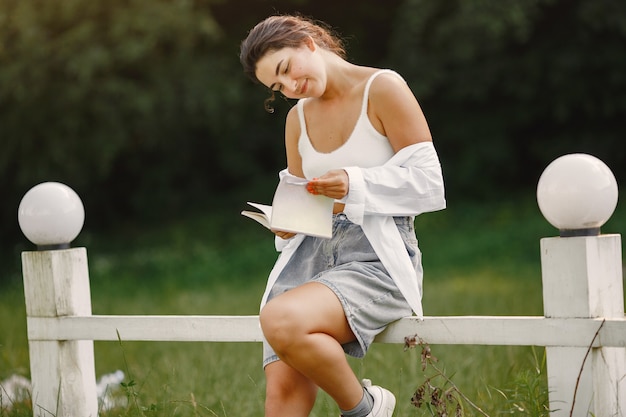 Retrato de mujer hermosa. La mujer lee un libro. Dama con camisa blanca.
