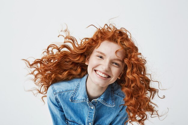 Retrato de mujer hermosa pelirroja alegre con pelo rizado volando sonriendo riendo.