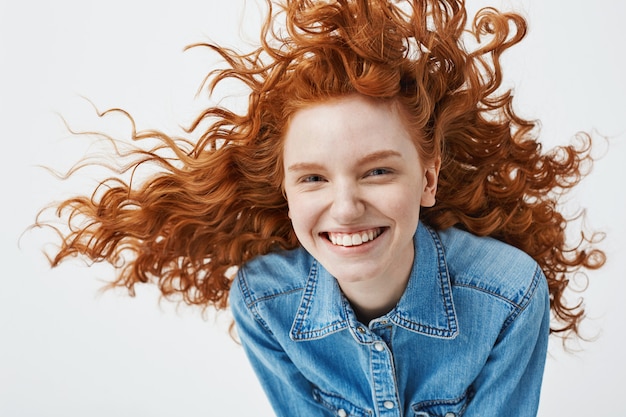 Retrato de mujer hermosa pelirroja alegre con pelo rizado volando sonriendo riendo.